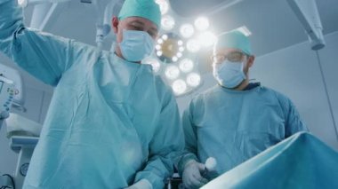 Ameliyat sırasında iki cerrahın ameliyat odasında, enstrümanlı hastanın üzerine eğilme sırasında düşük açılı atış. Modern Hastanedeki Profesyonel Doktorlar