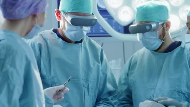 Chirurgen mit Augmented-Reality-Brille zur Durchführung modernster Operationen in technologisch fortschrittlichen Krankenhäusern. Ärzte und Assistenten arbeiten im Operationssaal zusammen. — Stockvideo