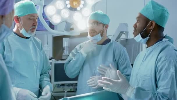 Équipe diversifiée de chirurgiens professionnels, d'adjoints et d'infirmières pratiquant une chirurgie invasive sur un patient dans la salle d'opération de l'hôpital. Les chirurgiens discutent activement pour sauver la vie d'un patient . — Video