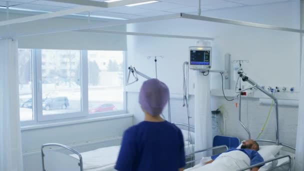 Sjuksköterskan tar hand om en patient som ligger i sängen. Rent modernt sjukhus med vänlig och professionell personal. — Stockvideo