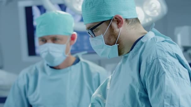 Équipe diversifiée de chirurgiens professionnels, d'adjoints et d'infirmières pratiquant une chirurgie invasive sur un patient dans la salle d'opération de l'hôpital. Les chirurgiens parlent et utilisent des instruments. Véritable hôpital moderne avec équipement authentique . — Video