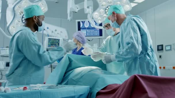 Разнообразная команда профессиональных хирургов, выполняющих инвазивную хирургию пациента в операционной больницы. Использование хирургов и других инструментов. — стоковое видео