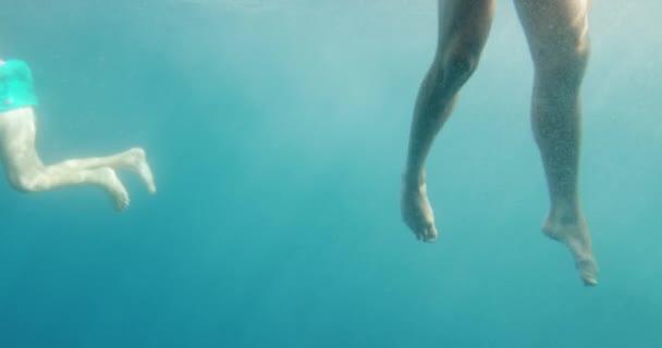 Zwei Personen, die im Meer schwimmen. Unterwasseraufnahme von Beinen im Meer. — Stockvideo