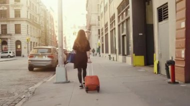 Big Sunny City ile Tekerlekli Bavul Sürükleyen Güzel Kırmızı Saçlı Kadın Back View Shot following.