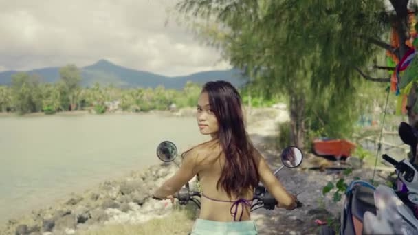 Gyönyörű ázsiai nő a Scooter indul vezetés egy sziklás út a tenger közelében. — Stock videók