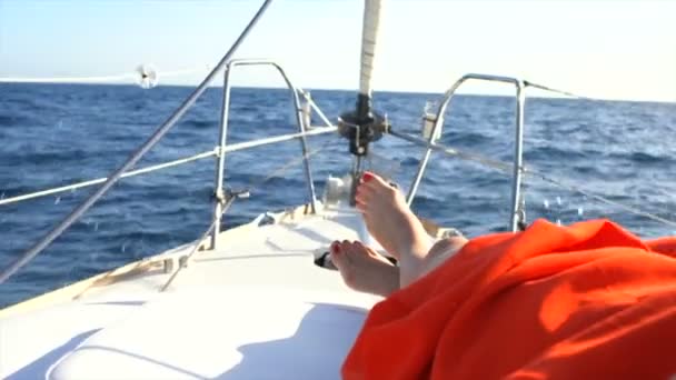 Mooie vrouw benen in de boeg van het zeiljacht. Zeilboot met diepblauwe zee en heldere hemel. — Stockvideo