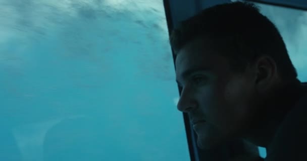 Zblízka na muže, který se dívá na podmořský život, když je na lodi se skleněným dnem.