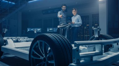 Otomobil Mae ve kadın tasarım mühendisleri elektrikli araba platformu şasi prototip üzerinde çalışan, 3D Concept için CAD yazılımı kullanarak. Otomotiv yenilik tesis araç çerçevesi lastikler, süspansiyon, motor ve pil ile