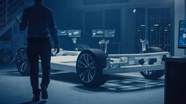 Автомобильный инженер входит в Инновационный центр автомобильной промышленности для работы на платформе электрошасси, используя дополненную реальность с программным моделированием 3D САПР. Инновационная начинка: VW с колесами, двигателем, батареей — стоковое фото