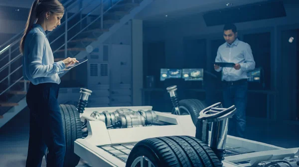 Autóipari mérnökök csapata dolgozó elektromos autó alváz platform, intézkedések meghozatala, együttműködve 3D CAD szoftver, elemzése hatékonyság. Jármű váz kerekekkel, motor és akkumulátor — Stock Fotó