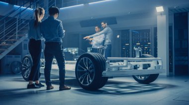 Takım Otomotiv mühendisleri tartışmak ve tasarım elektrikli araba platformu şasi prototip, tedbirler alma, 3D CAD yazılımı ile çalışma, kalite kontrol kontrol. Tekerlekler, motor ve batarya ile araç çerçevesi.