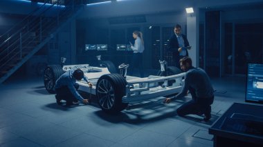 Otomotiv mühendisleri ekibi elektrikli araba platformu şasi üzerinde çalışma, önlemler alma, 3D CAD yazılımı ile çalışma, verimlilik analiz. Tekerlekler, motor ve batarya ile araç çerçevesi.