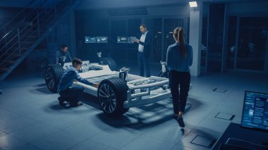 Otomotiv mühendisleri ekibi elektrikli araba platformu şasi üzerinde çalışma, önlemler alma, 3D CAD yazılımı ile çalışma, verimlilik analiz. Tekerlekler, motor ve batarya ile araç çerçevesi.