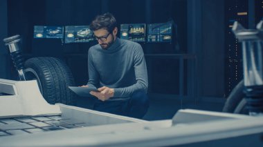 Otomobil Tasarım Mühendisi oturma yanında Hybrid elektrikli araba şasi platform prototip, kullanma tablet bilgisayar için tasarım geliştirme. Süspansiyon, jantlar, motor ve pil ile araç çerçevesi ile tesis