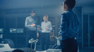 Otomobil mühendisleri tartışmak ve tasarım elektrikli araba şasi platformu, 3D CAD yazılımı ile tablet bilgisayarları kullanarak. Otomotiv yenilik tesis araç çerçevesi tekerlek, motor ve pil ile