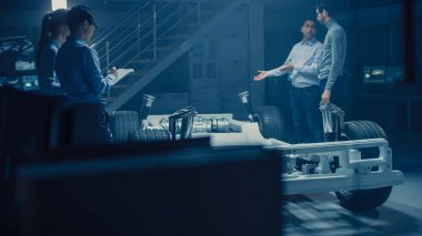 Otomobil mühendisleri elektrikli araba şasi platformu üzerinde çalışan, 3D konsept için CAD yazılımı ile tablet bilgisayar Augmented gerçeklik kullanma. Otomotiv yenilik tesis araç çerçevesi tekerlek, motor ve pil ile