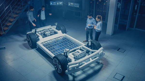 전기 자동차 섀시 플랫폼에서 일하는 자동차 엔지니어 팀, 조치를 취하고, 3D Cad 소프트웨어로 작업하고, 효율성을 분석합니다. 바퀴, 엔진 및 배터리가있는 차량 프레임. — 스톡 사진