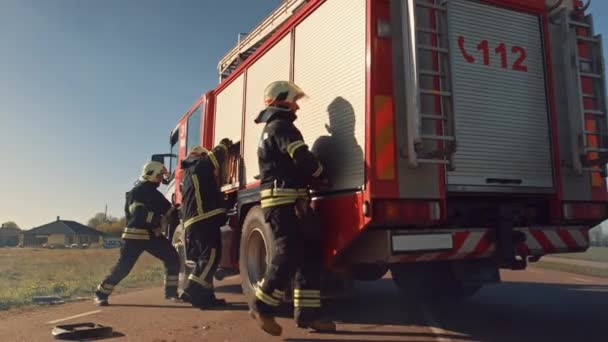 Rettungsteams der Feuerwehr treffen mit ihrem Löschfahrzeug an der Absturzstelle ein. Feuerwehrleute packen ihre Ausrüstung, bereiten Feuerwehrschläuche und Ausrüstung aus Feuerwehrauto vor, eilen zur Hilfe für Verletzte. — Stockvideo