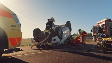 Trafik Kazası Olay Yeri İnceleme Ekibi: Ambulans ve İtfaiyeciler Kurtarma Ekibi, Rollover Aracında Tuzağa Düşenleri Kurtardı. Profesyoneller kurbanları temizler, ilk yardımı yapar, yangını söndürür.