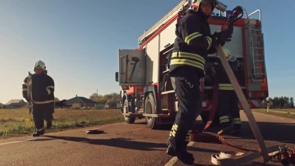 Equipe de resgate de bombeiros chegam ao acidente, catástrofe, local de incêndio em seu motor de incêndio. Bombeiros pegam seus equipamentos, preparam mangueiras de incêndio e engrenagem do caminhão de bombeiros, correm para ajudar pessoas feridas . — Vídeo de Stock