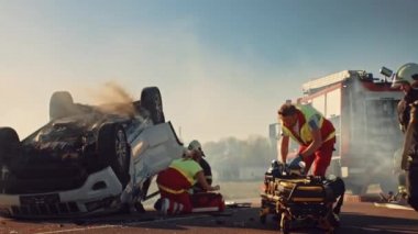 Araba kazasında trafik kaza sahnesinde: ambulans ve Itfaiyeciler kurtarma yaralı kurbanlar araç sıkışmış. Medics kullanın sedye, Ilk yardım gerçekleştirin. İtfaiyeciler kapmak ekipmanları. Yavaş hareket