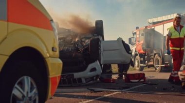 Trafik Kazası Olay Yeri İnceleme: Sağlık görevlileri ve İtfaiyeciler Yaralı Kurbanlar Aracın içinde Sıkıştı. Sıhhiyeciler sedye kullanır, ilk yardım uygular. İtfaiyeciler, İtfaiye 'den ekipmanları alın.
