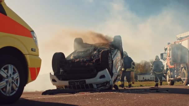 No acidente de carro Cena de acidente de trânsito: paramédicos e bombeiros salvam vítimas feridas presas no veículo. Os médicos usam macas, realizam primeiros socorros. Bombeiros agarram equipamento. Movimento lento — Vídeo de Stock