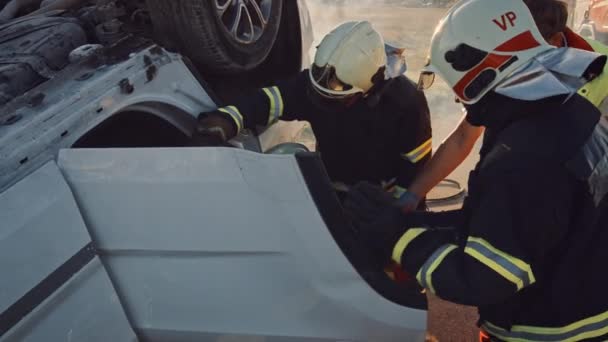 На місці аварії на автомобілі: рятувальна команда пожежників витягує жертву з транспортного засобу, вони обережно використовують розтяжки, передають її парамедикам, які виконують першу допомогу — стокове відео