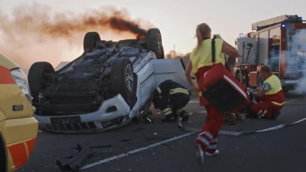 Autounfall: Sanitäter und Feuerwehrleute retten Verletzte aus eingeklemmten Opfern Sanitäter leisten einer Passagierin Erste Hilfe. Feuerwehr setzt hydraulischen Schneidspreizer ein, um Fahrzeug zu öffnen — Stockvideo