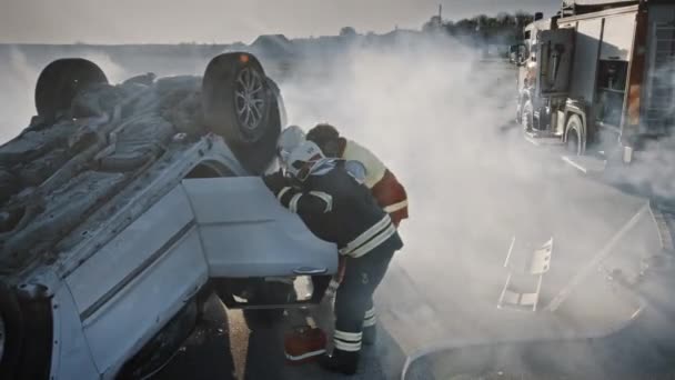 Sur les lieux de l'accident de la route : L'équipe de secours des pompiers sort la victime féminine du véhicule de basculement, ils utilisent des civières avec précaution, la livrent aux ambulanciers qui effectuent les premiers soins — Video