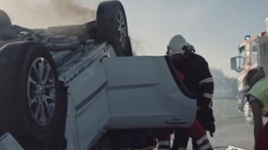 Trafik kazası: Sağlık görevlileri ve itfaiyeciler, takla atan araçta mahsur kalan yolcuları kurtarma planı. Sıhhiyeciler sedyeleri ve ilk yardım ekipmanlarını hazırlayın. İtfaiyeciler Hidrolik Kesiciler Kullansın