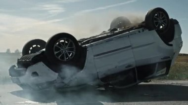 Korkunç Trafik Kazası Sigara İçen ve Yanan Araç Çarpışmadan Sonra Yolun Ortasında Çatısında Yatıyor. Hasarlı Arabalı Gündüz Çarpışması. Düşük Açı Düşük Karşıtlık Vuruşu