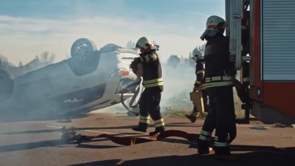 Reddingsteam van brandweerlieden arriveren bij de crash, catastrofe, brandweerplaats op hun brandweerauto. Brandweerlieden grijpen hun apparatuur, bereiden brandslangen en vistuig uit Fire Truck, Rush om mensen te helpen verwonden. — Stockvideo