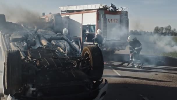 Rescue Team of Firefighters Arrive at the Crash, Catastrophe, Fire Site on their Fire Engine. Firemen Grab their Equipment, Prepare Fire Hoses and Gear from Fire Truck, Rush to Help Injured People. — Stock Video