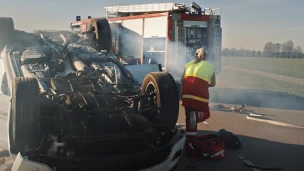 Reddingsteam van brandweerlieden en paramedici werken aan een verschrikkelijke auto-ongeluk. Voorbereiding apparatuur, rekken, EHBO. Bespaart gewonden en gevangen mensen van het brandende voertuig — Stockvideo