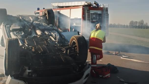 Squadra di salvataggio dei vigili del fuoco e paramedici Lavorare su una scena incidente stradale incidente d'auto terribile. Preparazione Attrezzature, Allungamenti, Pronto Soccorso. Salvare le persone ferite e intrappolate dal veicolo in fiamme — Video Stock