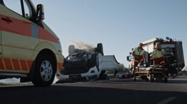 İtfaiyeciler ve Sağlık Ekibi Korkunç Trafik Kazası Olay Yeri İnceleme 'de çalışıyor. Ekipman, esneme, ilk yardım. Yaralı ve Tuzağa düşürülenlerin Yanan Araçtan Kurtarılması