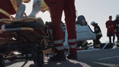 Araba kazasında trafik kazası: Itfaiyeciler anne bir çocuk sedye üzerinde yatan yardım kim tasarruf/resuscitate çalışıyor. Arka planda diğer kapana kısılmış yolcular ile rollover aracı