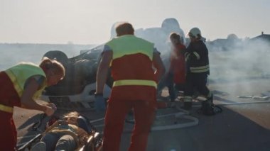 Araba kazasında trafik kaza sahnesinde: sağlık görevlileri küçük bir kız sedye üzerinde yatan hayat tasarruf, o Ilk yardım yardımı verildi. Firefighters ücretsiz diğer yolcular rollover araç kapana kısılmış