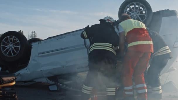 On the Car Crash Traffic Accident Scene: Rescue Team of Firefighters Pull Female Victim out of Rollover Vehicle, They Use Stretchers Carefully, Hand Her Over to Paramedics who Perform First Aid — Stock Video