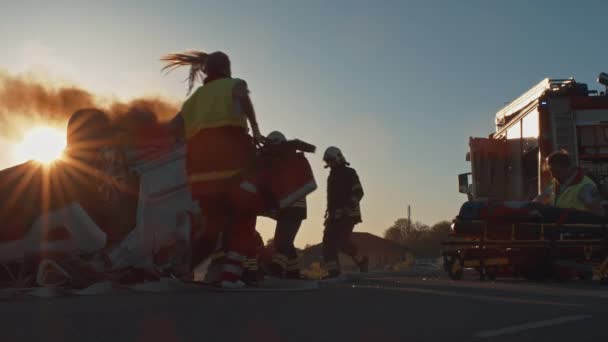 Accidente de tráfico: paramédicos y bomberos rescatan pasajeros atrapados en un vehículo rodante. Los médicos preparan equipos de primeros auxilios. Los bomberos utilizan separador de cortadores hidráulicos para abrir el vehículo — Vídeo de stock