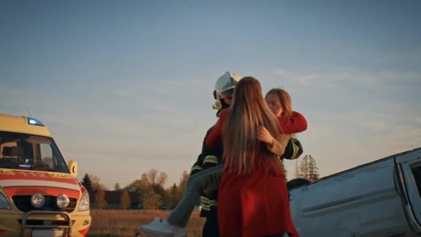 Děsivá scéna dopravní nehody při autonehodě: statečný hasič nosí zraněnou mladou dívku, kde se znovu sjednotilo s její milující matkou. Odvážní Záchranníci a hasiči zachraň životy — Stock video