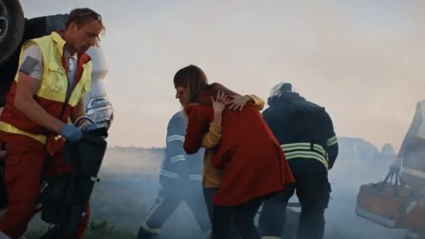 交通事故:負傷した少女は彼女の愛する母親と再会します.背景にある車と勇気ある救急車と消防士は命を救う — ストック動画