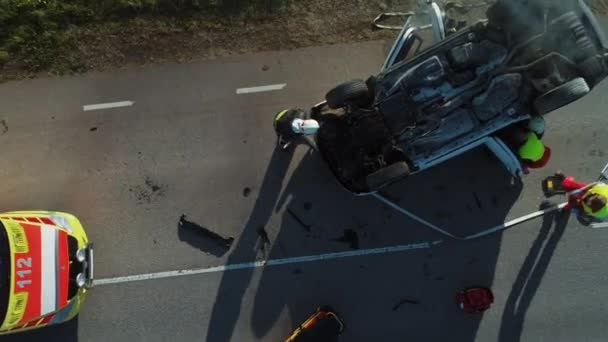 Vista aérea: Equipo de rescate de bomberos y paramédicos trabajan en una escena de accidente de tráfico. Preparación de equipos, primeros auxilios. Salvar a las personas heridas y atrapadas del vehículo. Acercar — Vídeos de Stock