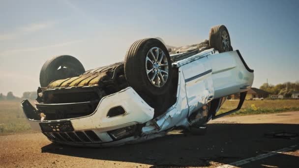 Incidente stradale terribile, Rollover fumare e veicolo in fiamme sdraiato sul tetto in mezzo alla strada dopo la collisione. Scena di incidente diurno con auto gravemente danneggiata. — Video Stock