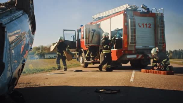 Einsatzkräfte der Feuerwehr treffen mit ihrem Löschfahrzeug am Unfallort ein. Feuerwehrmänner greifen nach Werkzeug, Ausrüstung und Ausrüstung aus Feuerwehrauto, eilen zu Verletzten, Verschütteten — Stockvideo