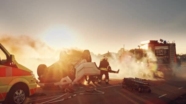 Na cena do acidente de trânsito do acidente de carro: Equipe de resgate de bombeiros retira vítima feminina do veículo Rollover, eles usam macas com cuidado, entrega-a aos paramédicos que realizam primeiros socorros — Vídeo de Stock