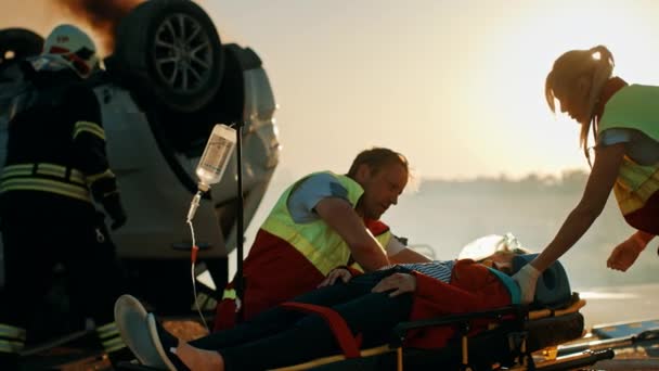 自動車事故事故のシーンで 救急隊員は ストレッチャーに横たわっている乗客の命を救います 彼らはハートビートに耳を傾け 酸素マスクを使用し ドロップカウンターを設定します 消防士は車を開くためにカッターを使用します — ストック動画