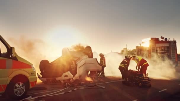 Na místě autonehody dopravní nehody: Záchranný tým hasičů vytáhnout ženské oběti z vozidla Rollover, oni používají nosítka opatrně, předat ji zdravotníkům, kteří provádějí první pomoc — Stock video