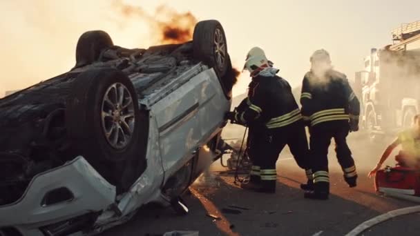O dopravní nehodě při autonehodě: Záchranáři a hasiči Zachraňte zraněné oběti v pasti. Doktoři dávají první pomoc ženám na nosítkách. Hasiči použít hydraulické řezačky rozmetadlo k otevření vozidla — Stock video
